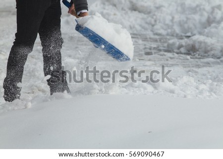 Business man with shovel cleaning snow filled street in front of the office at work