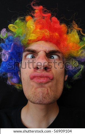 A silly crazy man wearing a clown wig with rainbow colors