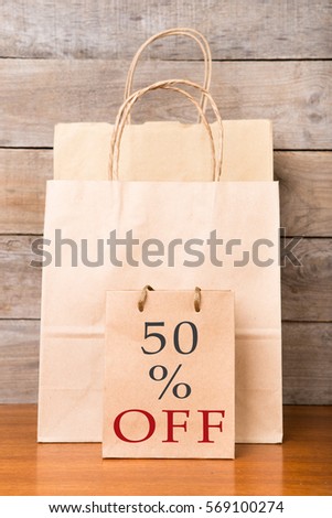 Shopping bags with inscription "50% OFF" on wooden background