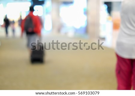 A man walking with pulling luggage toward airport terminal. Blur mode. Defocused.