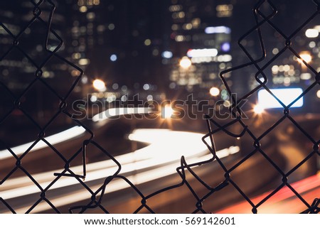 Nigh city bokeh lights through the wire mesh fence