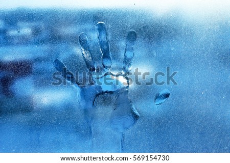 Human hands on frozen glass winter