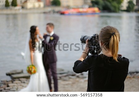 The girl photographer photographing a wedding in Prague against the background of the river