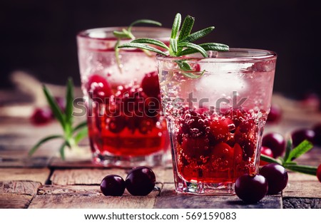 Cranberry beverage with ice and berries, vintage wooden background, selective focus