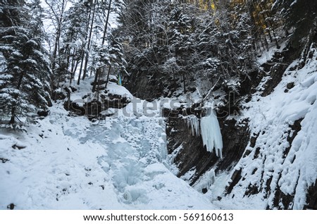 Frozen mountain waterfall in the winter forest. A large piece of ice in the mountains. Ice block.