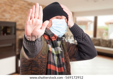 Sick man with protection mask against flu doing stop gesture with hand Royalty-Free Stock Photo #569172952