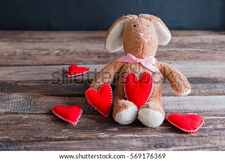 Fluffy toy bunny with felt hearts.  Postcard to Valentine's Day.