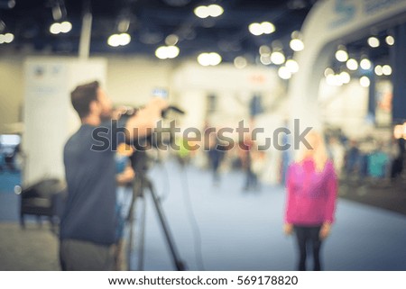 Blurred abstract of cameraman operator and assistant recording/videotaping an interview with a fit and lifestyle female athlete runner at the conventional hall of Marathon event expo. Vintage tone.