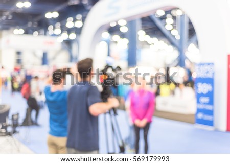 Blurred abstract of cameraman operator and assistant recording/videotaping an interview with a fit and lifestyle female athlete at the conventional hall of Marathon event expo in Houston, Texas, US.