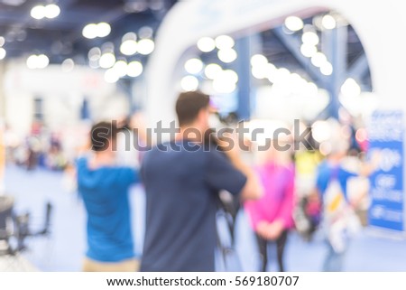 Blurred abstract of cameraman operator and assistant recording/videotaping an interview with a fit and lifestyle female athlete at the conventional hall of Marathon event expo in Houston, Texas, US.