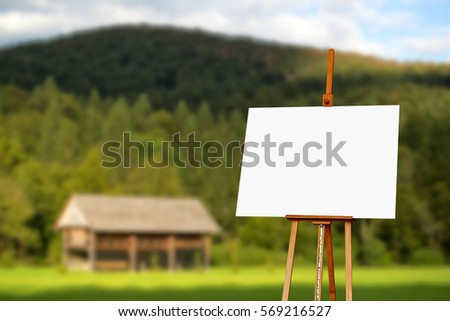 Blank painter artist canvas on easel with mountain in background, copy space for artistic picture or painting