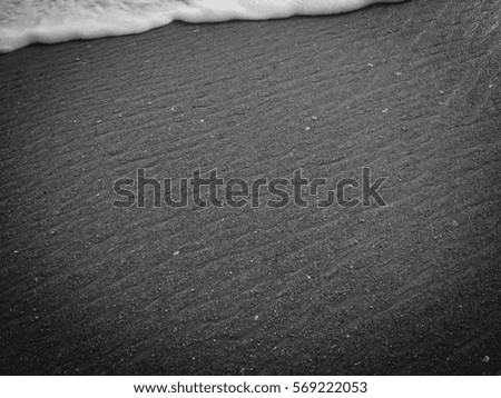 White ocean sea foam and black volcanic sandy surface beach backdrop top view background