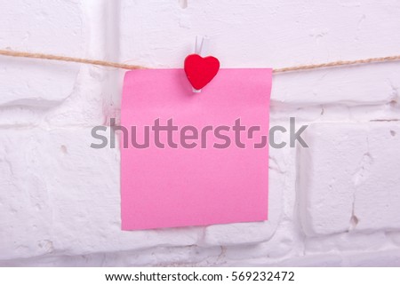 piece of paper on the clothespin and a heart on a white wall