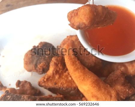 Horizontal photo of closeup fried fish with chili sauce on wooden table. Shallow depth of field. Copyspace