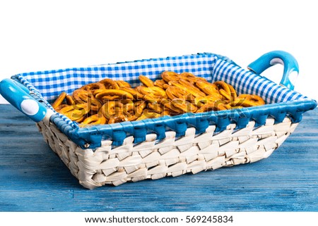 White wicker basket of bread with checkered cloth on blue background. Studio photo