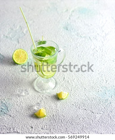 Sparkling water detox drink with lime, ice and spinach on a light background in transparent glass