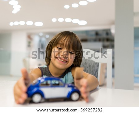 Happy kid at home with oldtimer car toy playing
