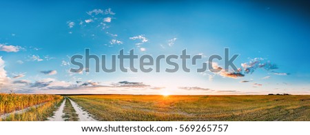 Sunset, Sunrise Over Rural Meadow Field And Country Open Road. Countryside Landscape With Path Way Under Scenic Summer Dramatic Sky In Sunset Dawn Sunrise. Sun Over Skyline Or Horizon.