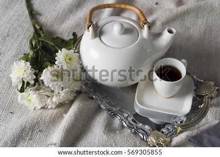Teapot with a small cup on the table.