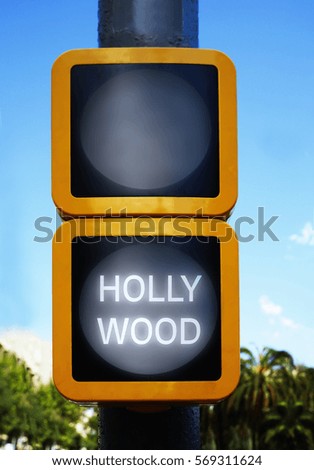 Green traffic light with word HOLLYWOOD on sky background