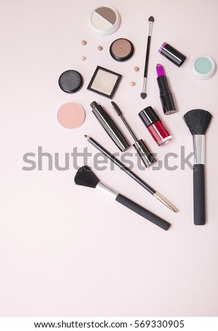 Make up products arranged on a pastel pink background with empty space below