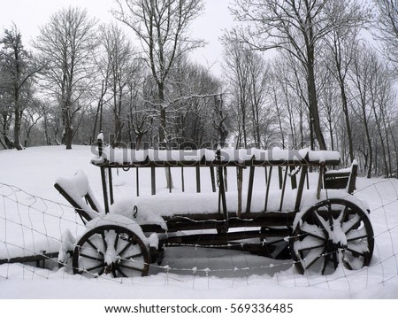 snowy historic wooden wagon standing on a rural farm