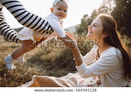 Young family with little daughter walking along the mountain slopes on the high yellow grass. Pope Shakes his daughter in arms, to kiss mother substitutes. family - this is happiness