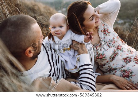 Young family with little daughter walking along the mountain slopes on the high yellow grass. family with daughter lying on the grass in the mountains 