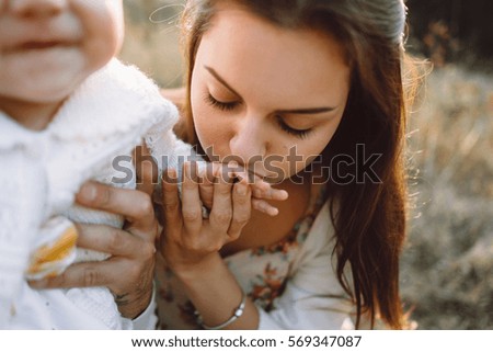 Young family with little daughter walking along the mountain slopes on the high yellow grass. happiness is in your hands. small life in the hands of. Mom kisses daughter fingers