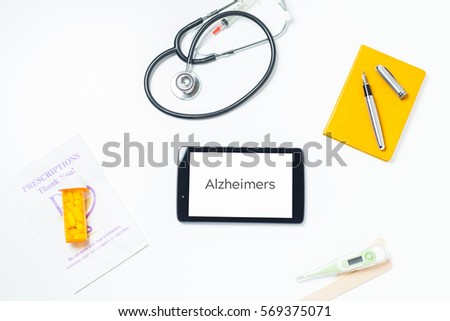 Wide Angle Photo Of Doctors Tablet On Desk With Alzheimers Typed On Screen With Notebook.