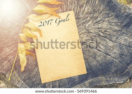 a piece of paper and writing on the wood with dry leaves