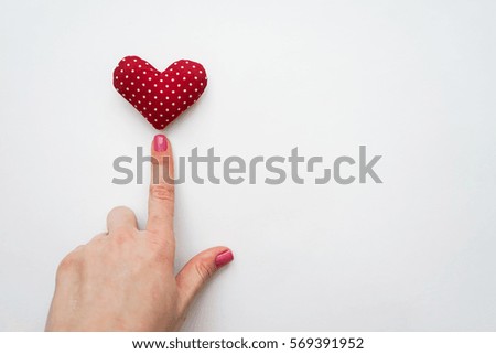 Woman hand pointing to handmade Valentines day heart isolated on white