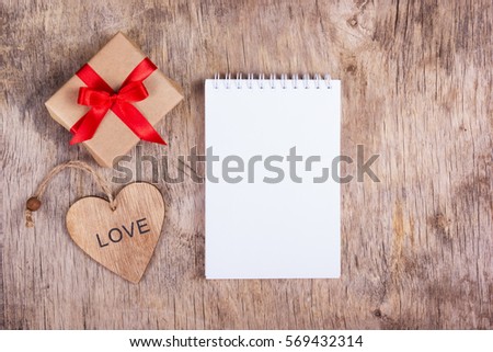 Notepad with blank page, a surprise and a wooden heart. Notepad with blank pages and a surprise valentine wood. Copy space. Valentine's Day.