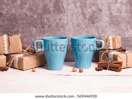 Two blue coffee cups, gifts on a white wooden and grey concrete background