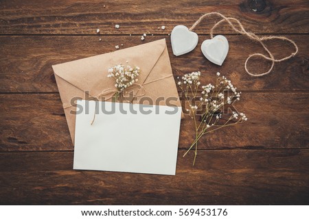 Empty greeting card and flowers with hearts on wooden background 