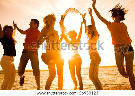 group of happy young people dancing at the beach on  beautiful summer sunset