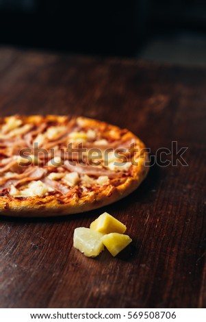 Delicious fresh pineapple pizza served on wooden table, brown background with copy space