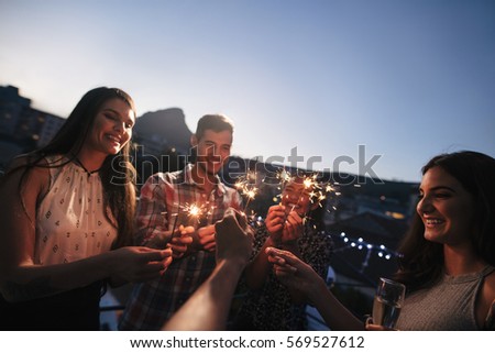 Group of friends enjoying rooftop party with sparklers. Young people enjoying new years eve.