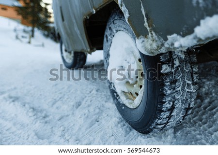 Cropped photo of car covered with snow. Winter tires on snow. car tire in snow