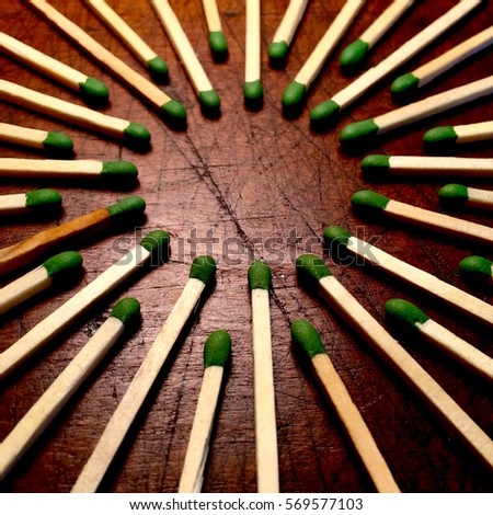 Circle of matches on a scarred wood background, with small center space for text.