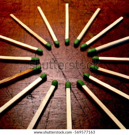 Circle of matches on a scarred wood background, with space for text.