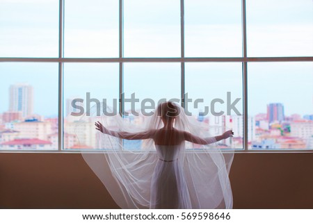 Bride looking into huge window and dreaming of future