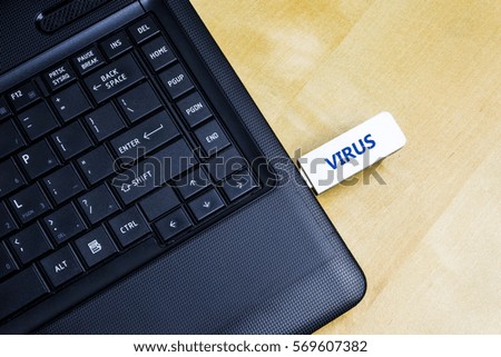 A USB Flash Drive with inscription virus plugged into a laptop.