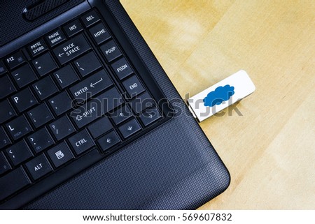 A USB Flash Drive with inscription cloud icon plugged into a laptop.