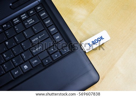 A USB Flash Drive with inscription E-book plugged into a laptop. 