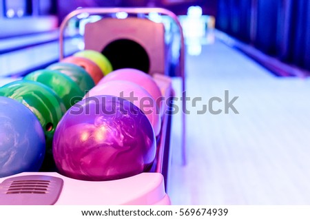 A Purple Bowling balls has ready for player to throwing ball on the wooden lane and in the bowling hall.