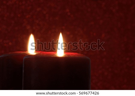 Red Candle Reflected in Mirror with Red Glitter Background - Photograph of a red burning candle reflected in a vintage mirror with a red sparkling background.  Selective focus on the front candle. 