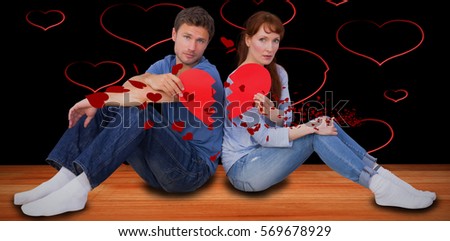 Couple holding a broken heart against red hearts floating