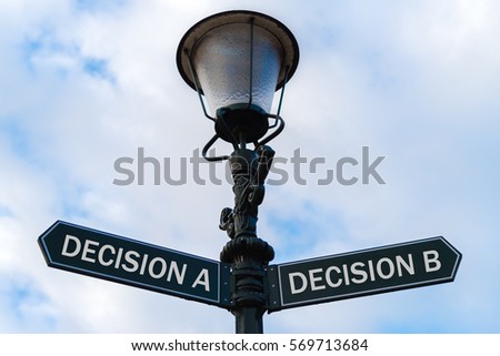 Street lighting pole with two opposite directional arrows over blue cloudy background. Decision A versus Decision B concept.