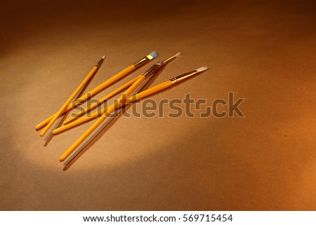 Five yellow paintbrushes on the brown floor